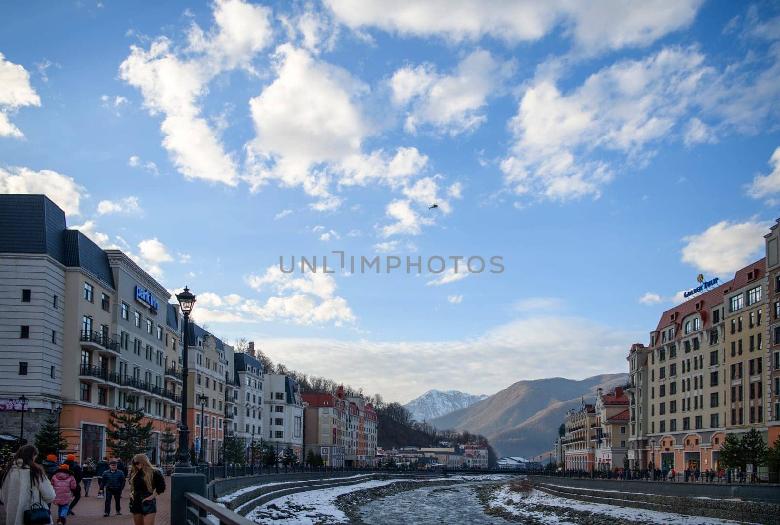 Sochi  Russia - January 02  2021: The Mzymta river in the Krasnaya Polyana resort. Tourists walk along the embankment