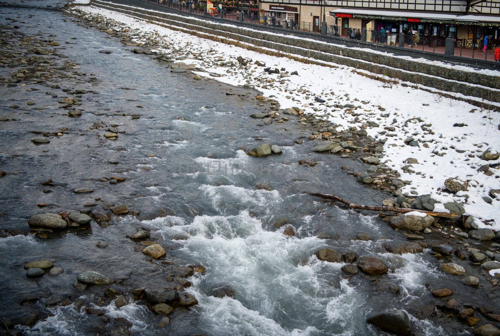 Sochi  Russia - January 02  2021: The Mzymta river in the Krasnaya Polyana resort. Tourists walk along the embankment