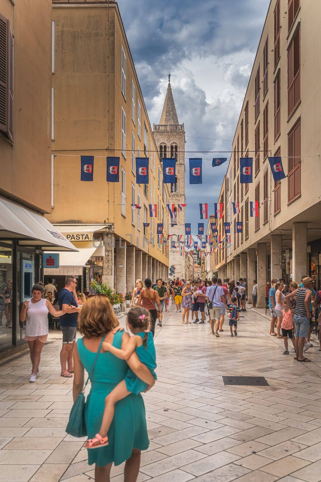 Zadar, Croatia, July 2019 Tourists visiting beautiful streets of the old town with bell tower of St. Donata Church in background