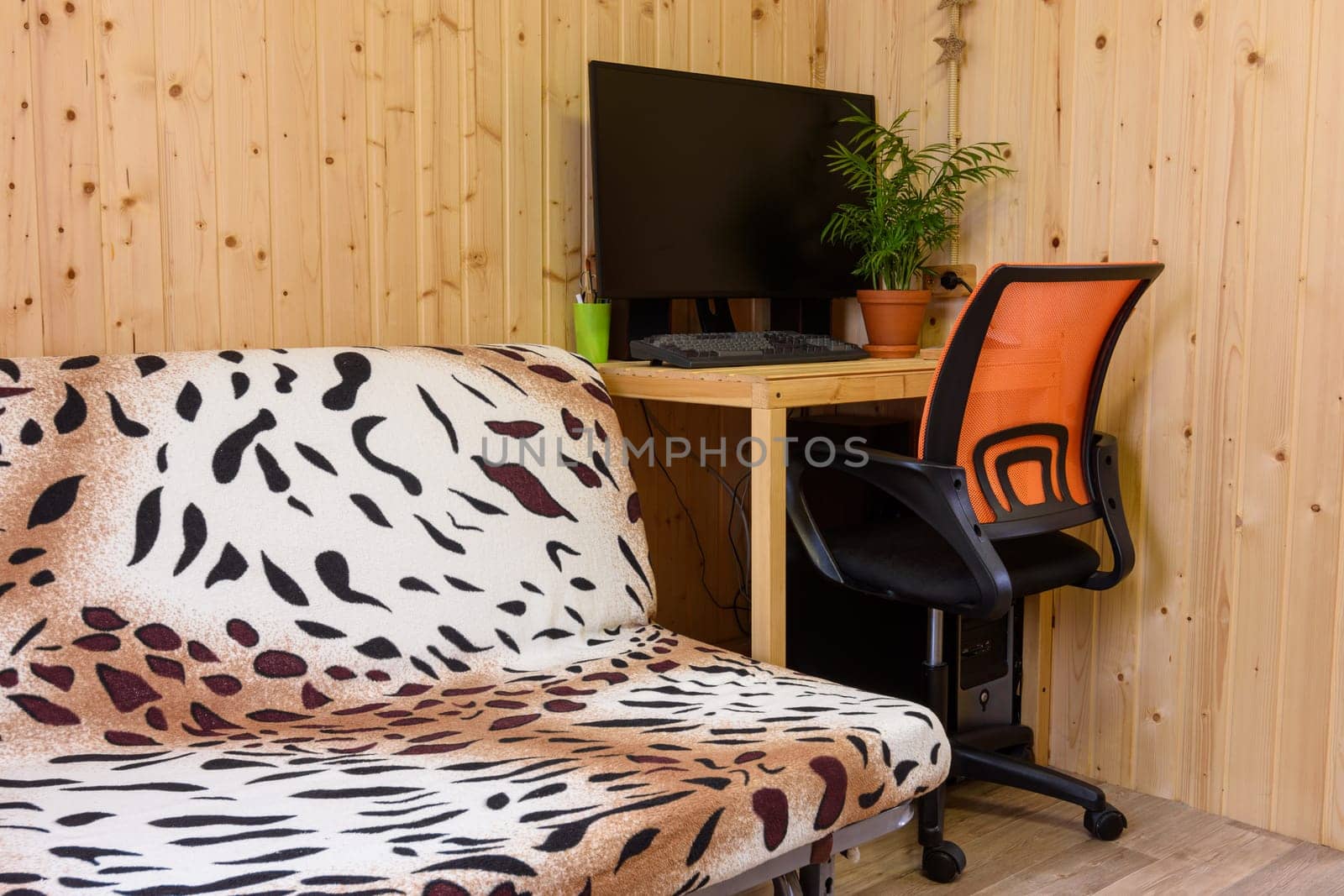 A fragment of the interior of a country house room, next to the sofa is a computer desk