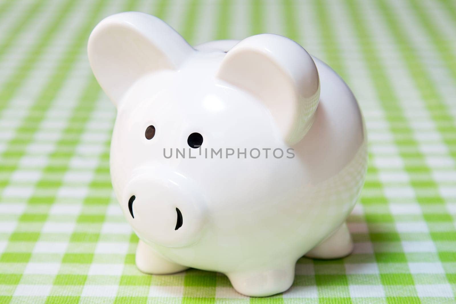 White piggy bank on the table with checkered tablecloth