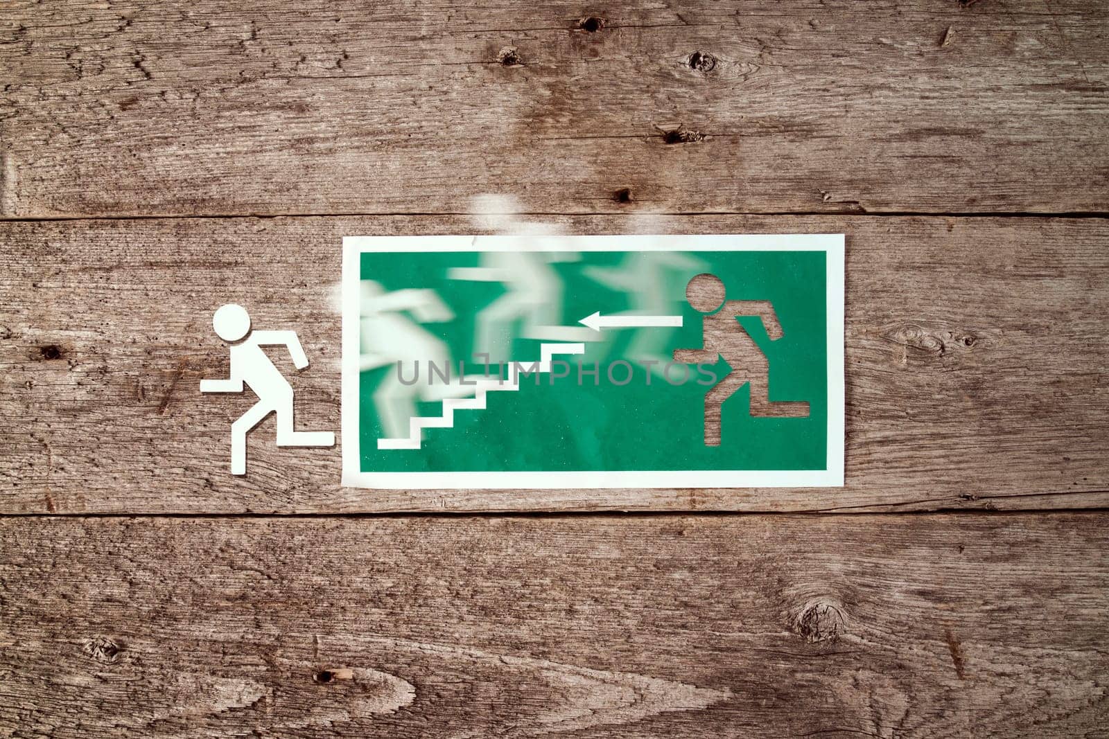 Exit sign on old wooden wall with man figure running to doorway