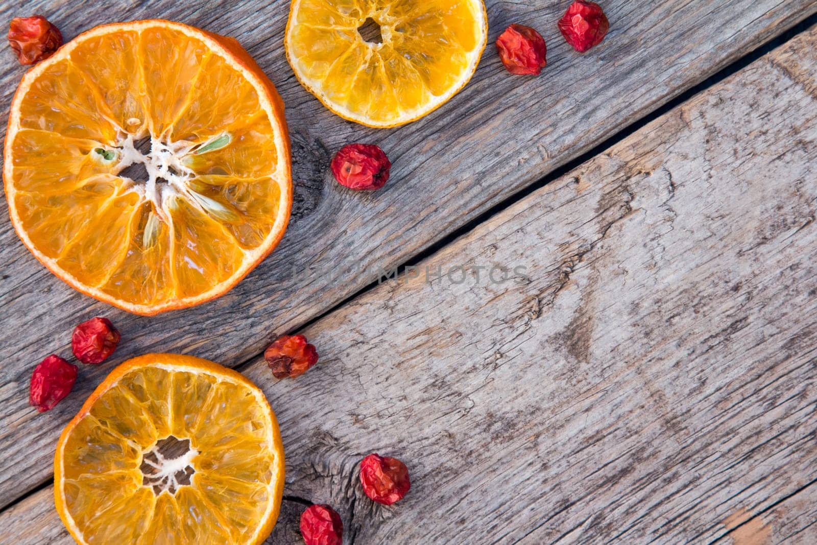 Dried oranges with ashberry on the old wooden background.