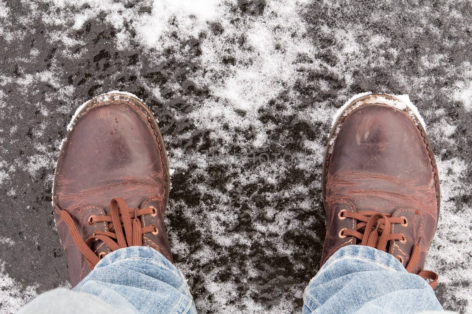 Male legs in leather shoes standing on frozen lake ice