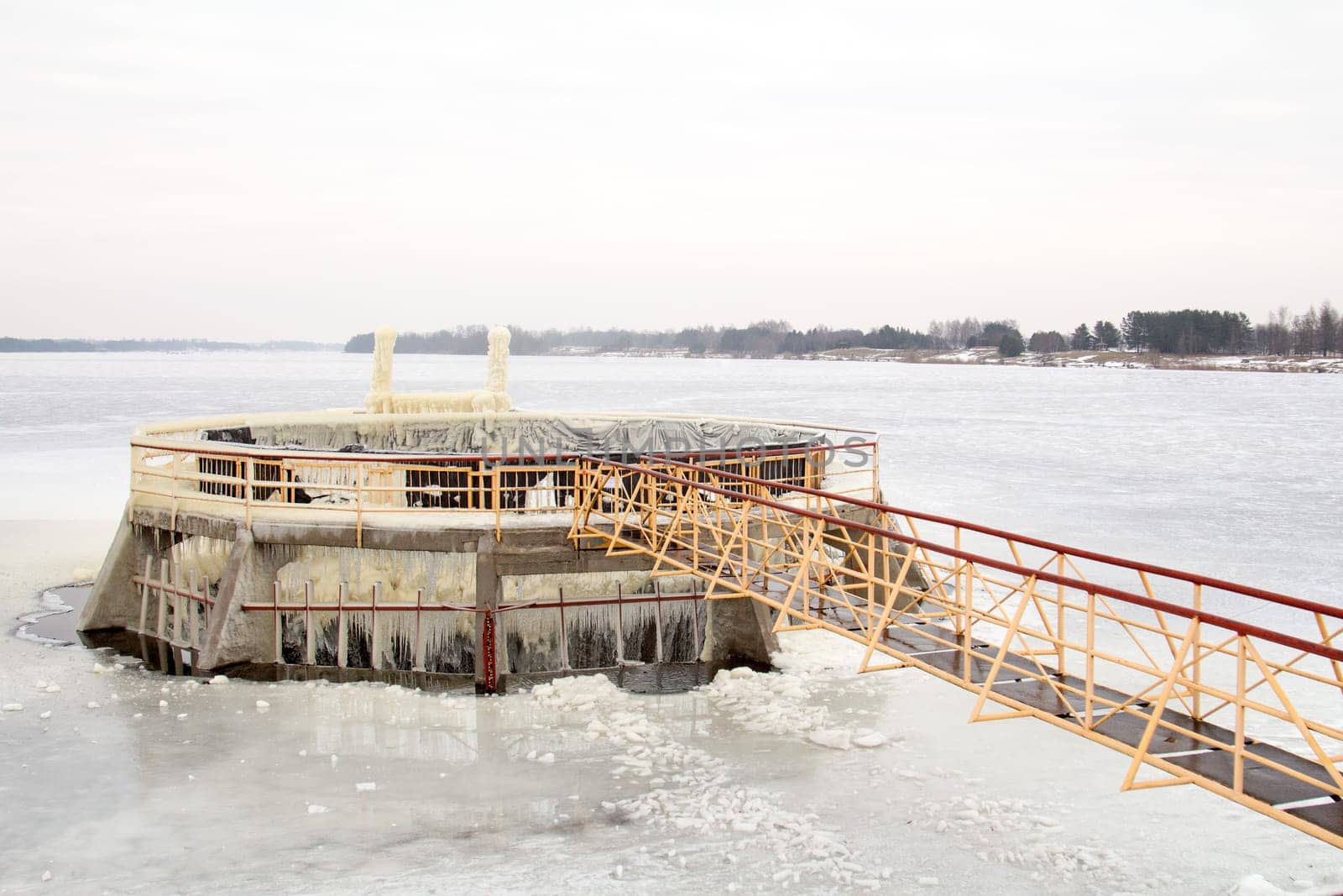 View of dam spillway in winter covered in snow and ice.