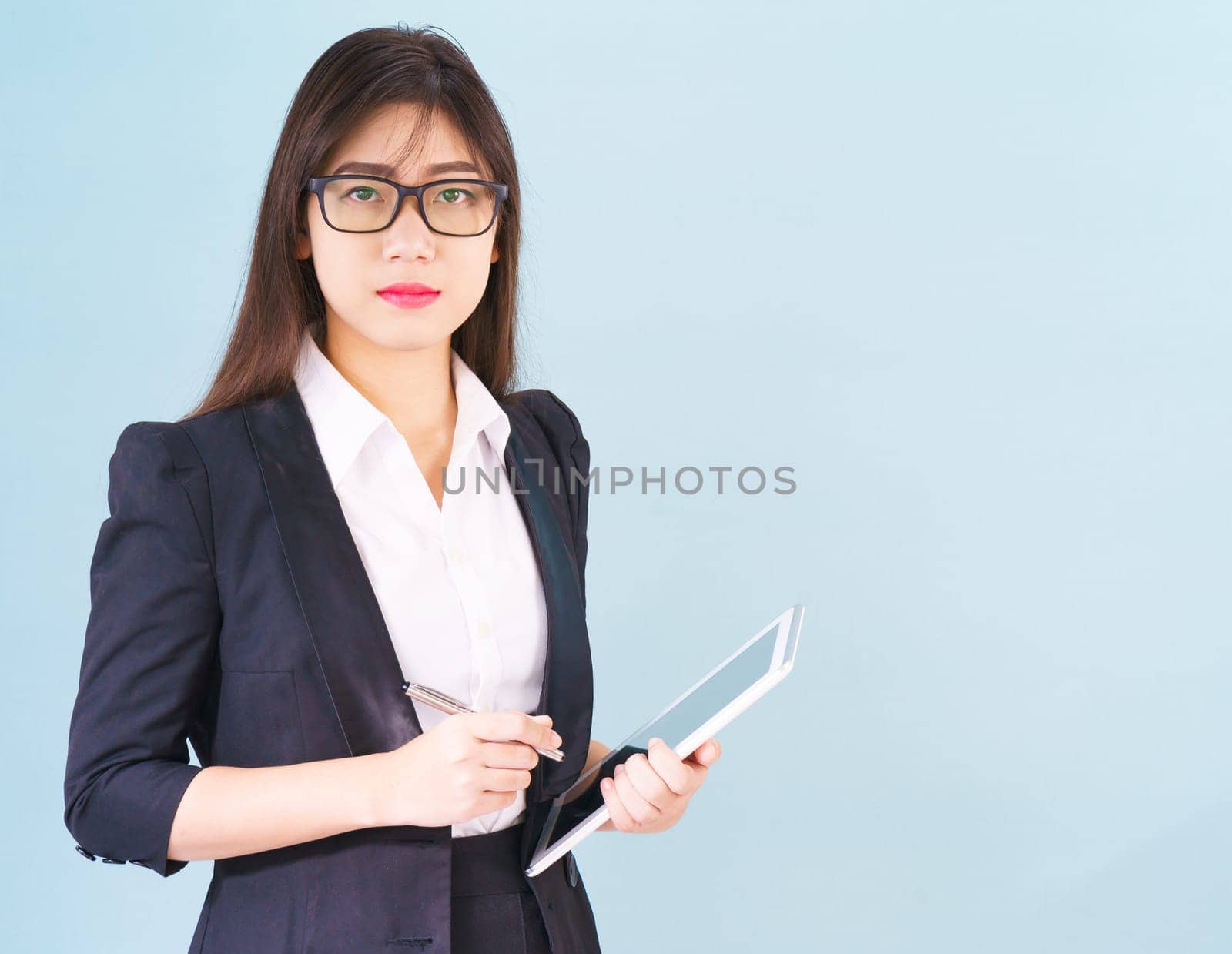 Young Asain women in suit standing using her digital tablet against blue background