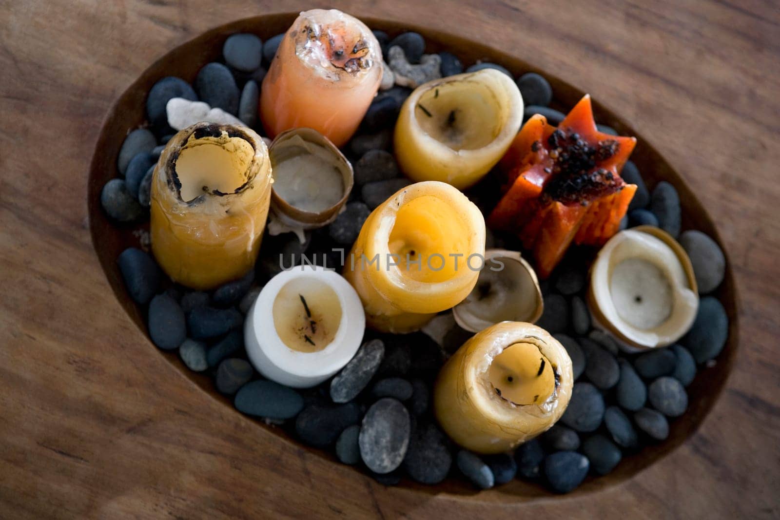 High angle view of candles and pebbles in a wooden tray