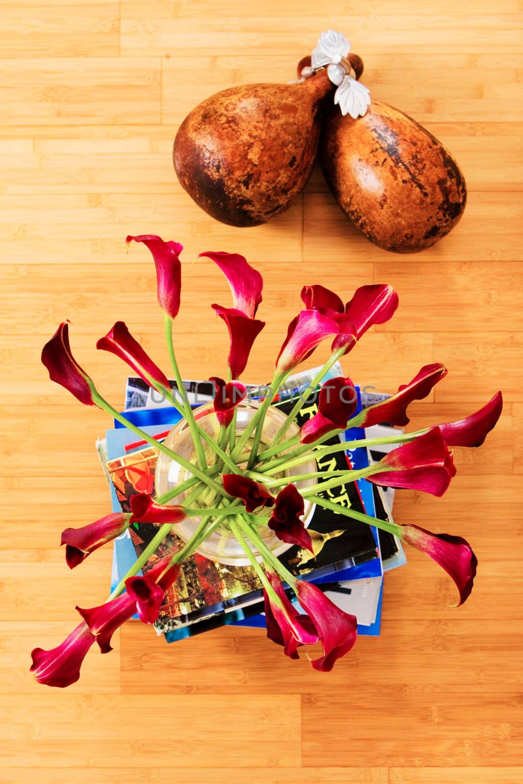 High angle view of flowers in a vase on a stack of books with dried gourds