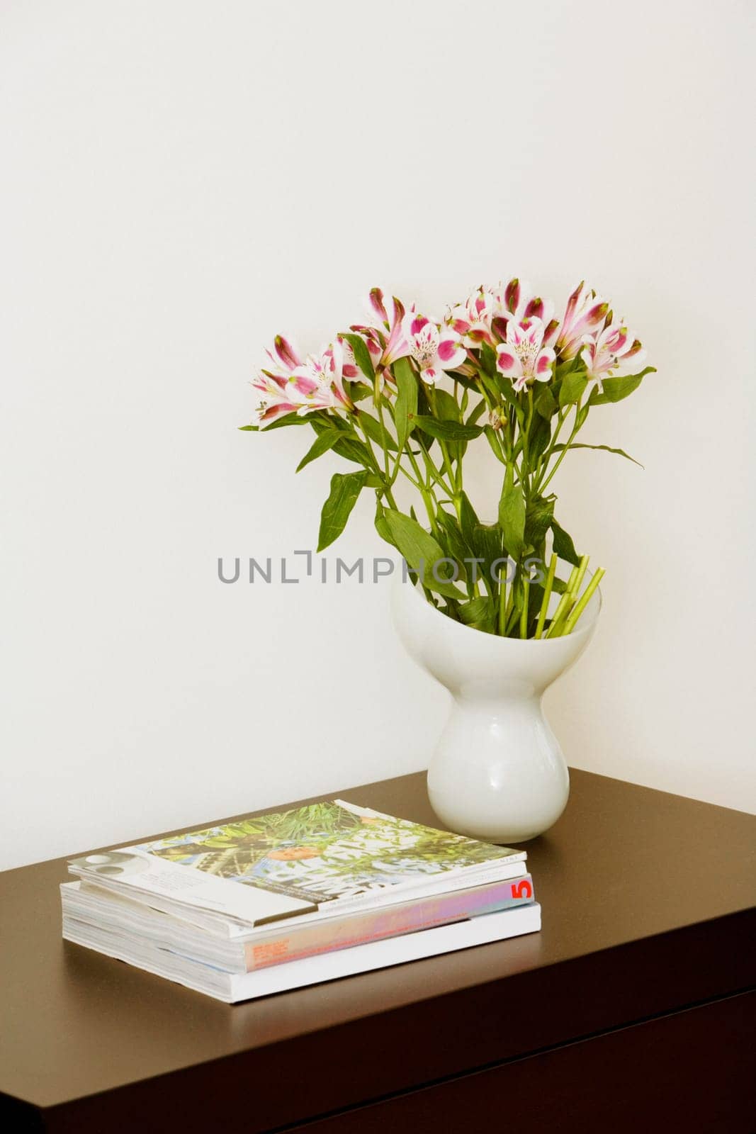Close-up of books and a flower vase on a side table