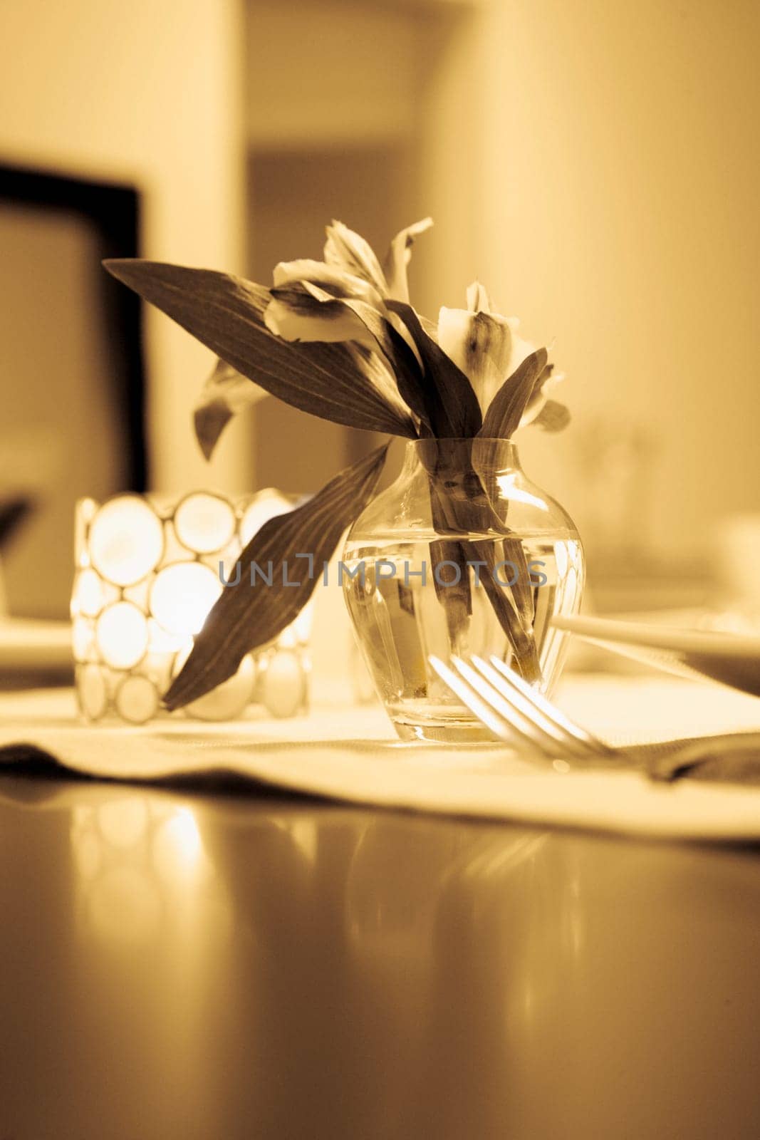 Close-up of a flower vase with a candlestick holder on a dining table