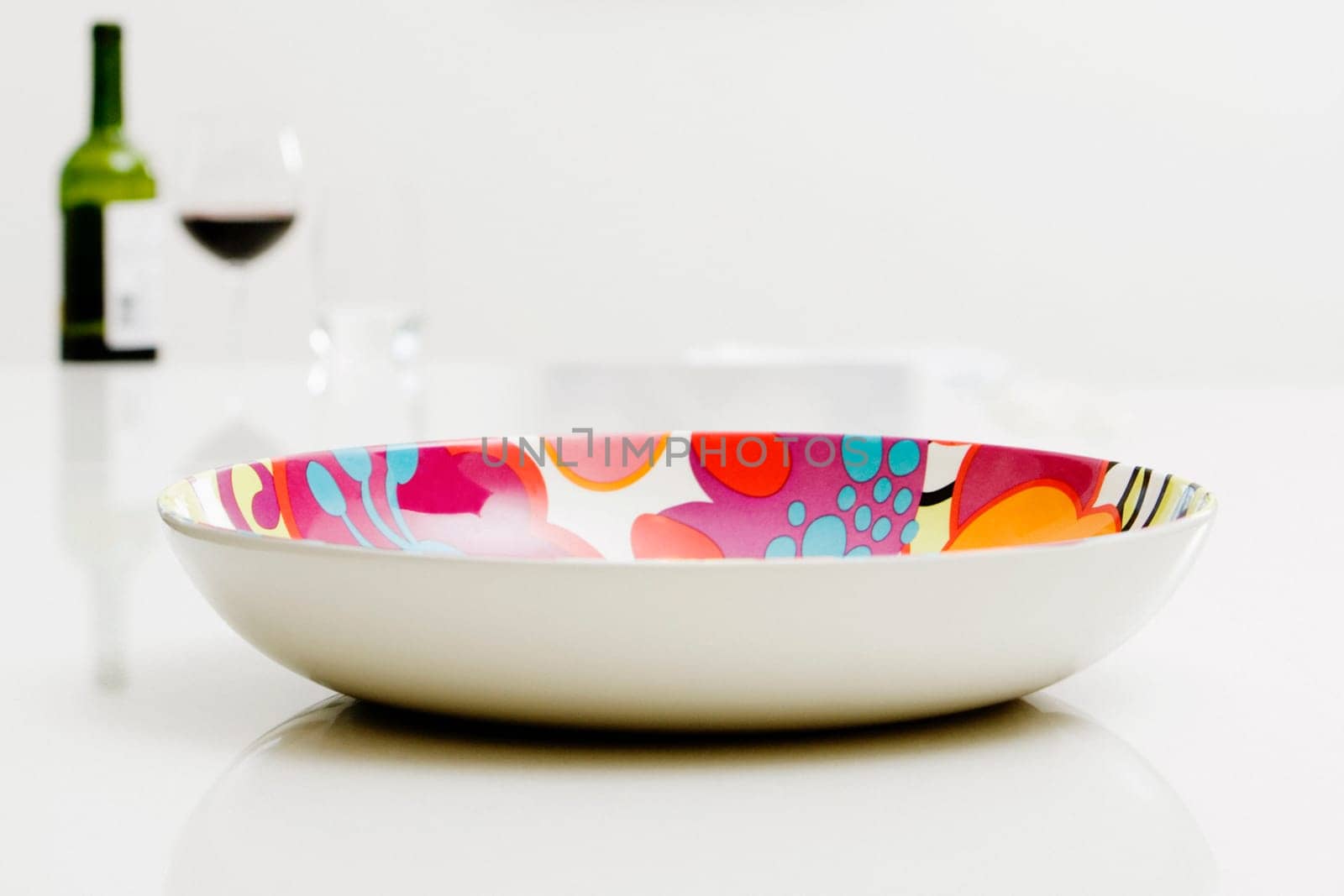 Close-up of a bowl with a bottle of red wine in the background