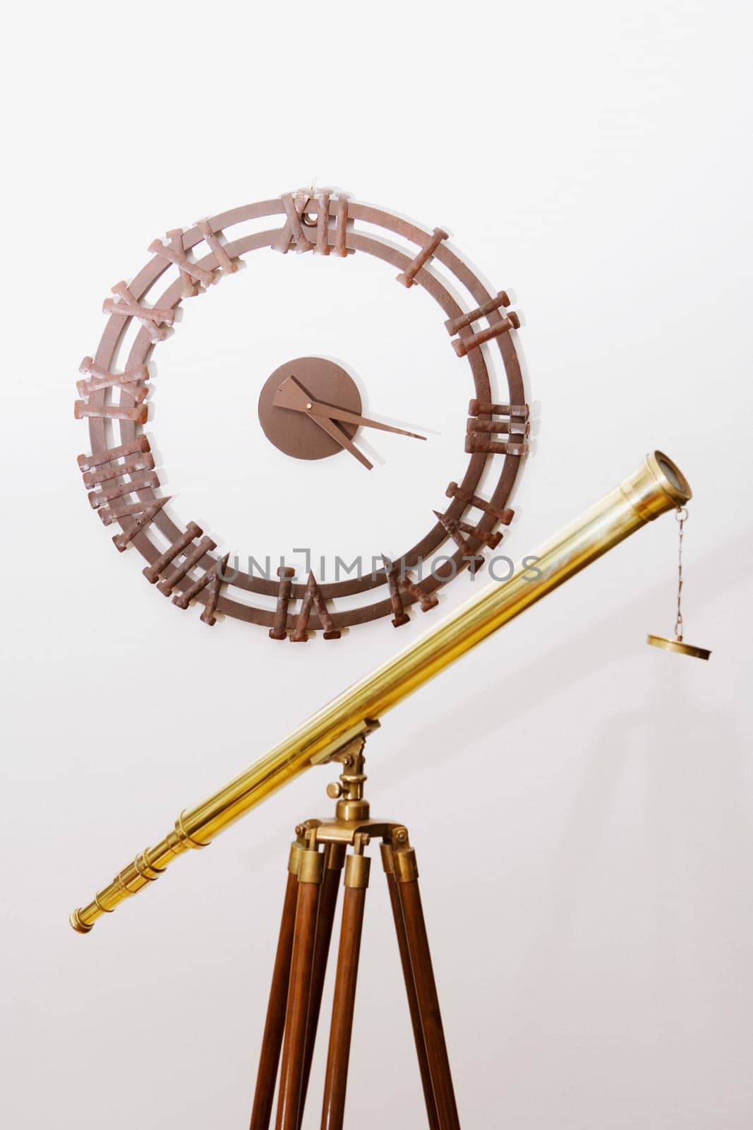 Telescope on a tripod with a clock on a wall