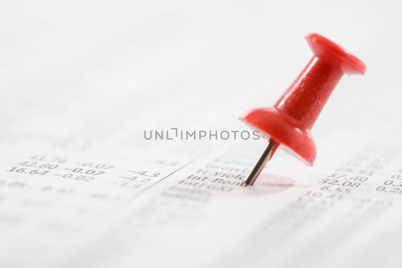 Close_up of a straight pin on a financial newspaper