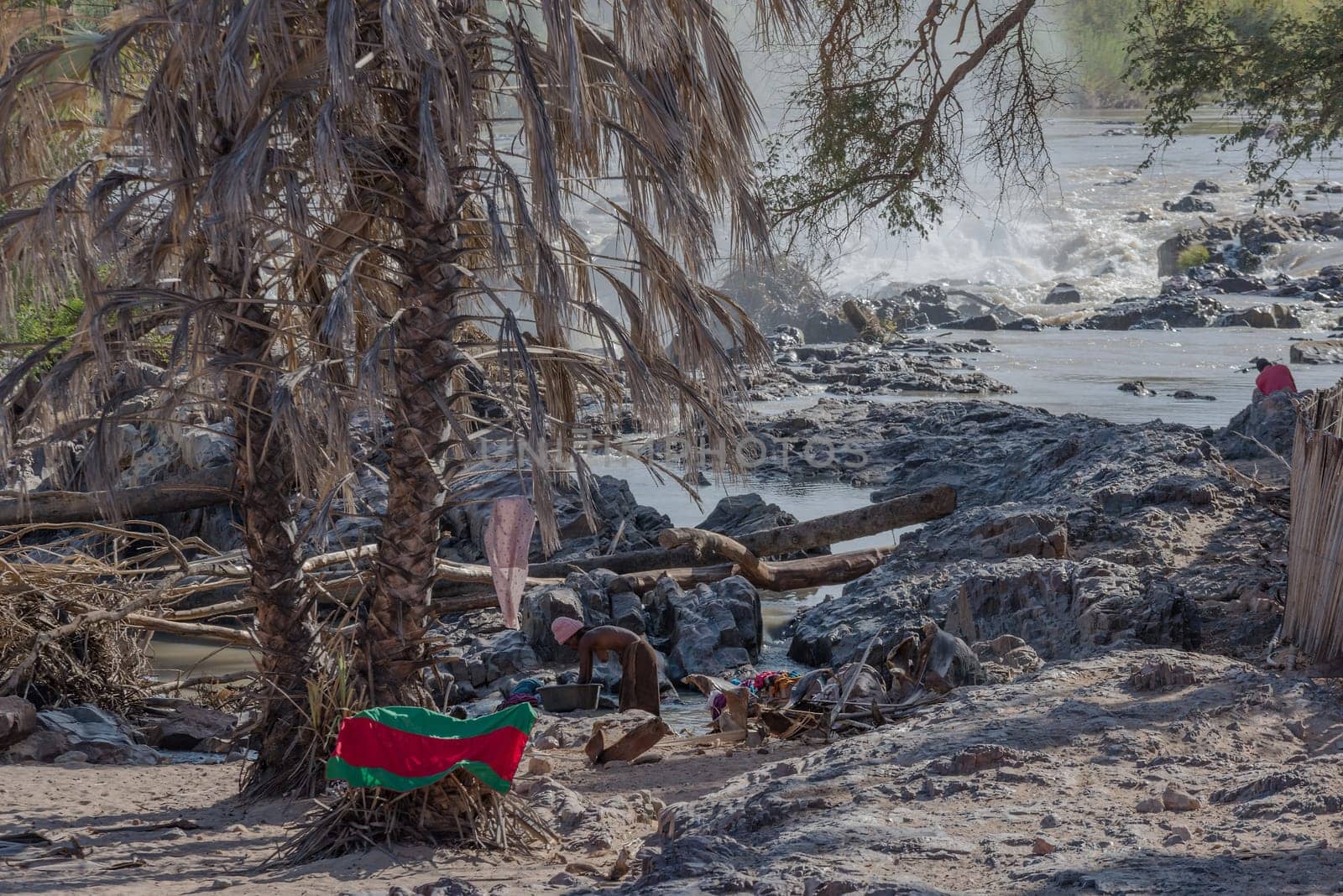 Unidentified Himba woman washing clothes at Epupa Falls, Kunene River, Namibia