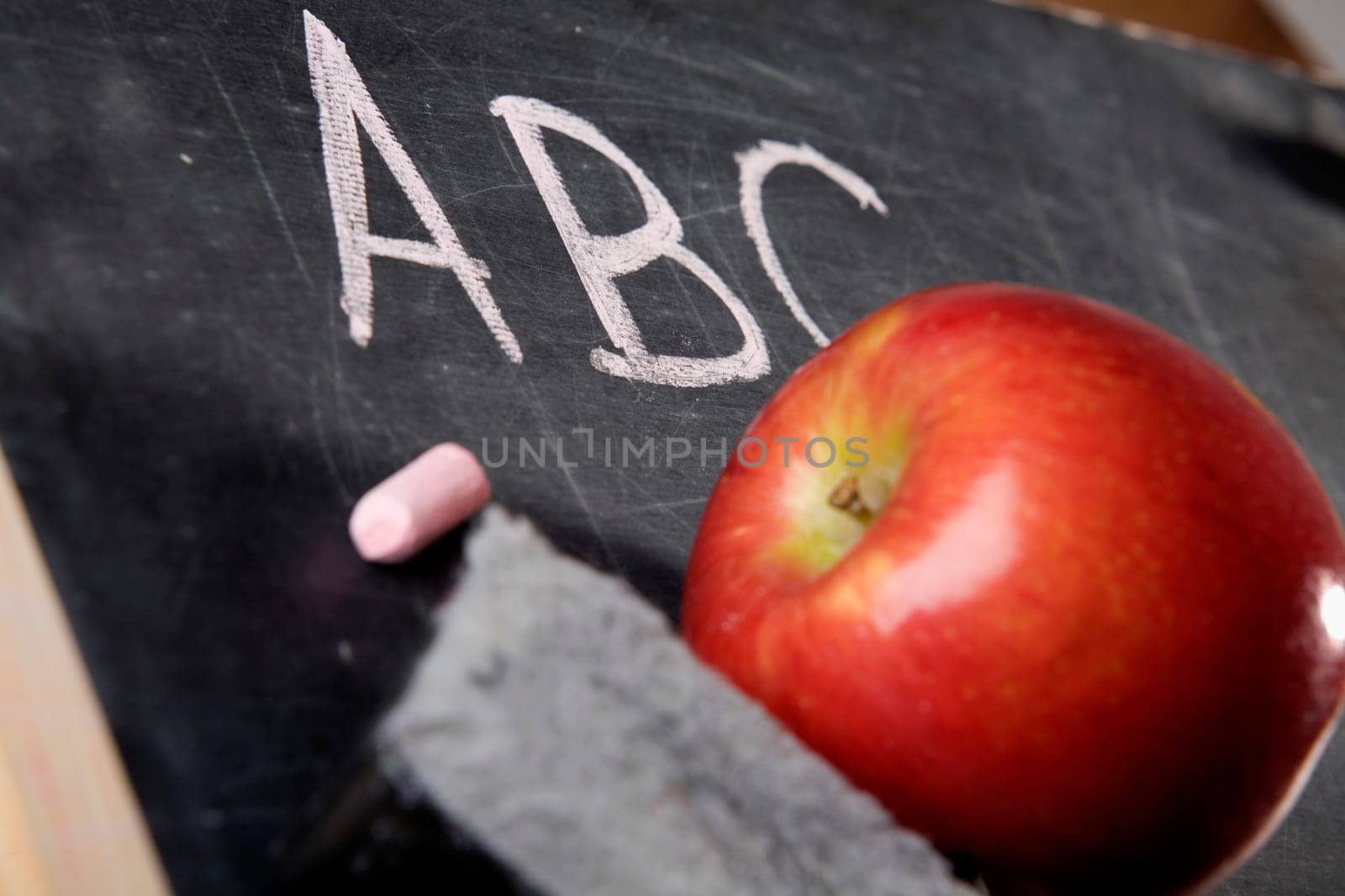 Close-up of an apple and a duster on a blackboard