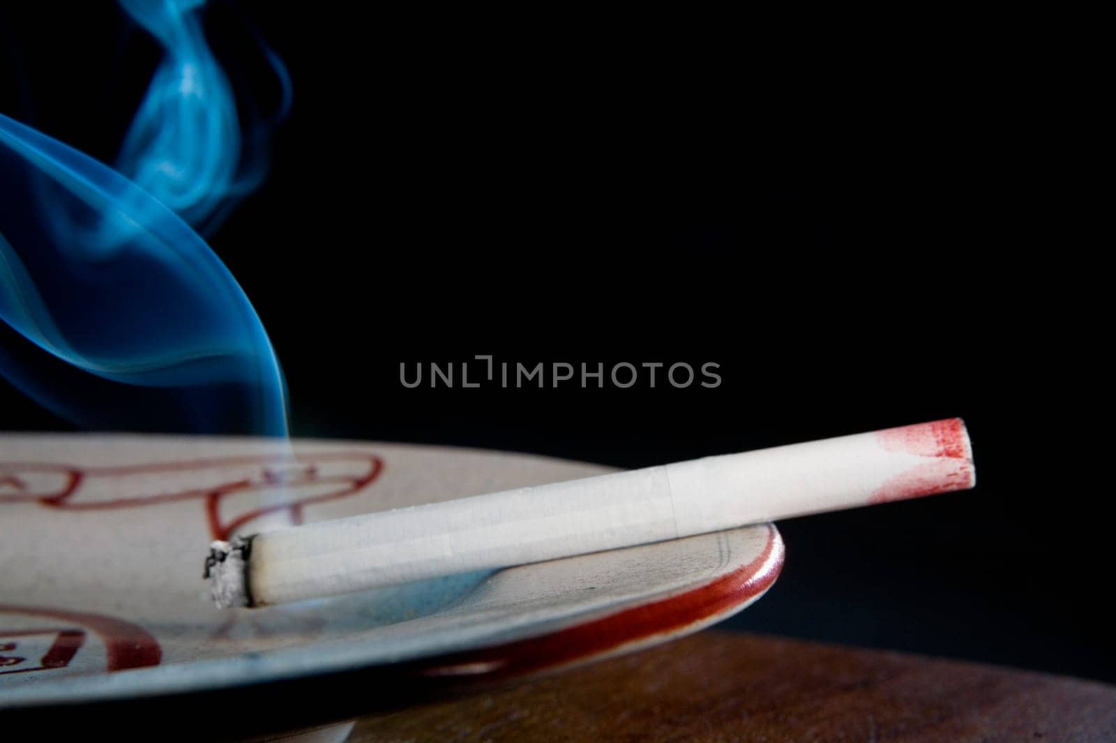 Close-up of a lipstick mark on a cigarette in an ashtray
