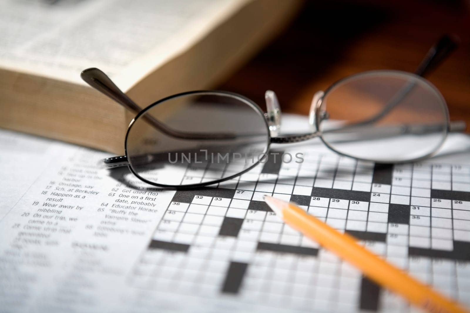 Close-up of a pencil and a pair of eyeglasses on a crossword puzzle