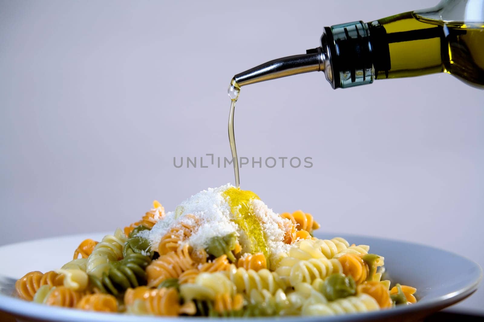 Olive oil being poured on a plate of pasta