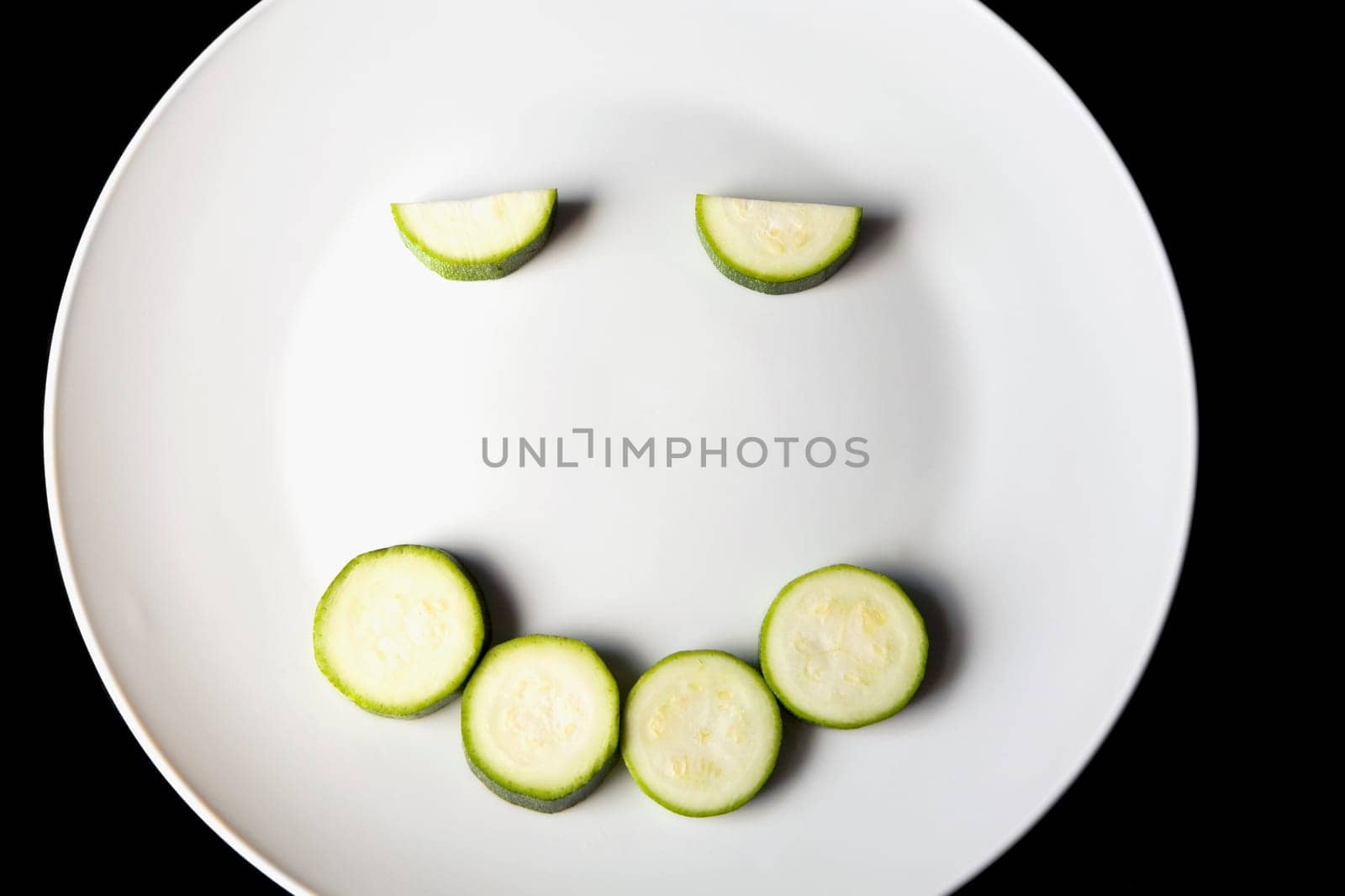 Close-up of slices of zucchini in a plate making a smiling face