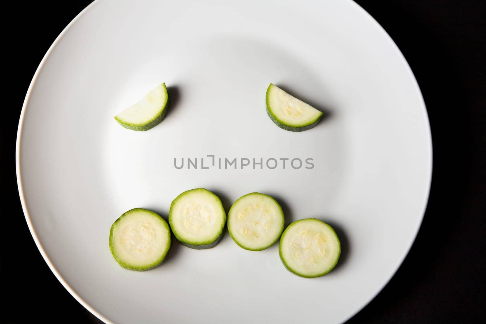 Close-up of slices of zucchini in a plate making a frowning face