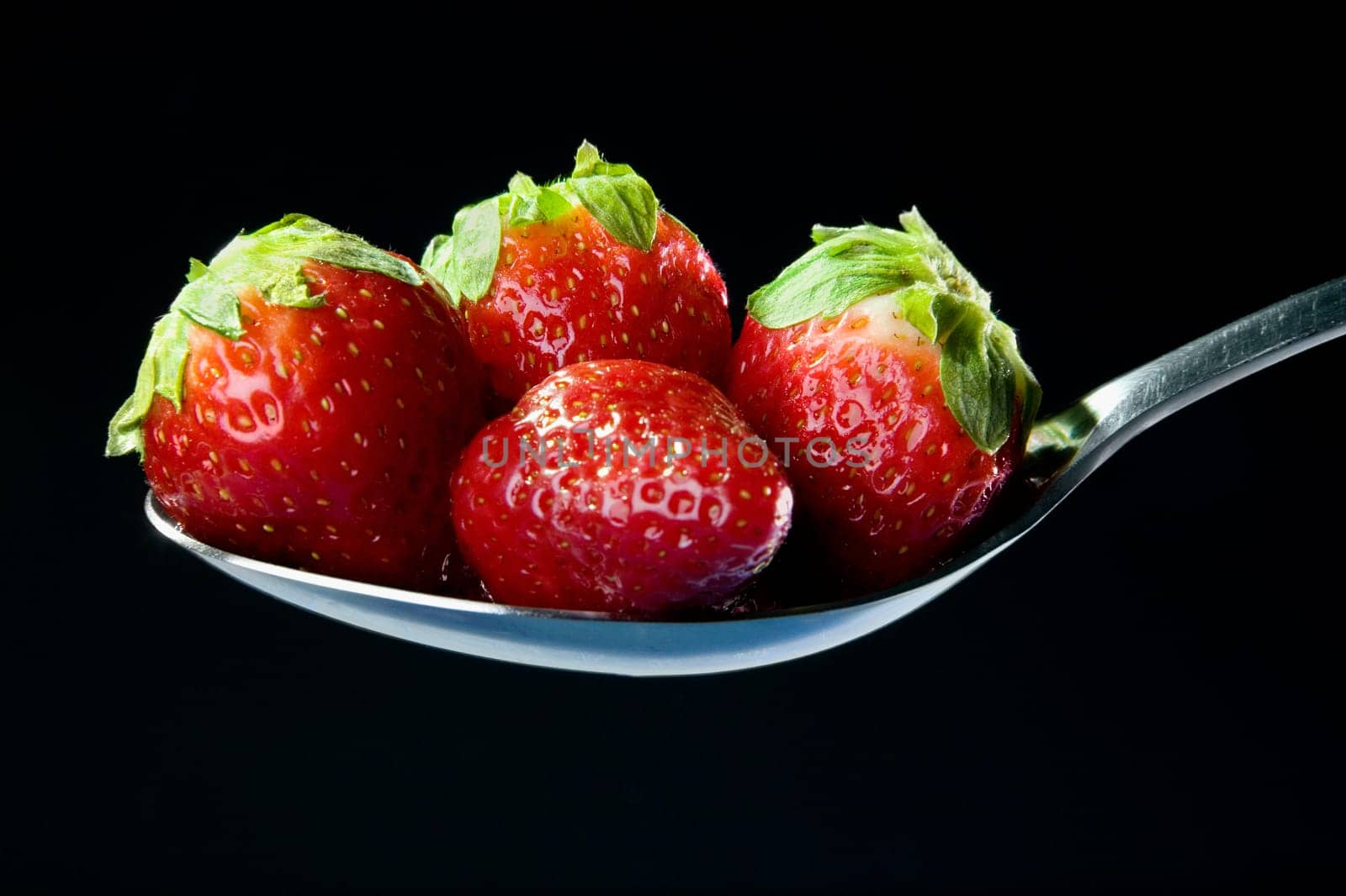 Close-up of four strawberries in a spoon