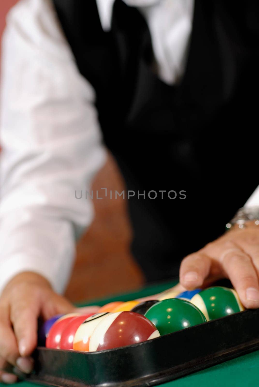 Mid section view of a man racking up pool balls on a pool table