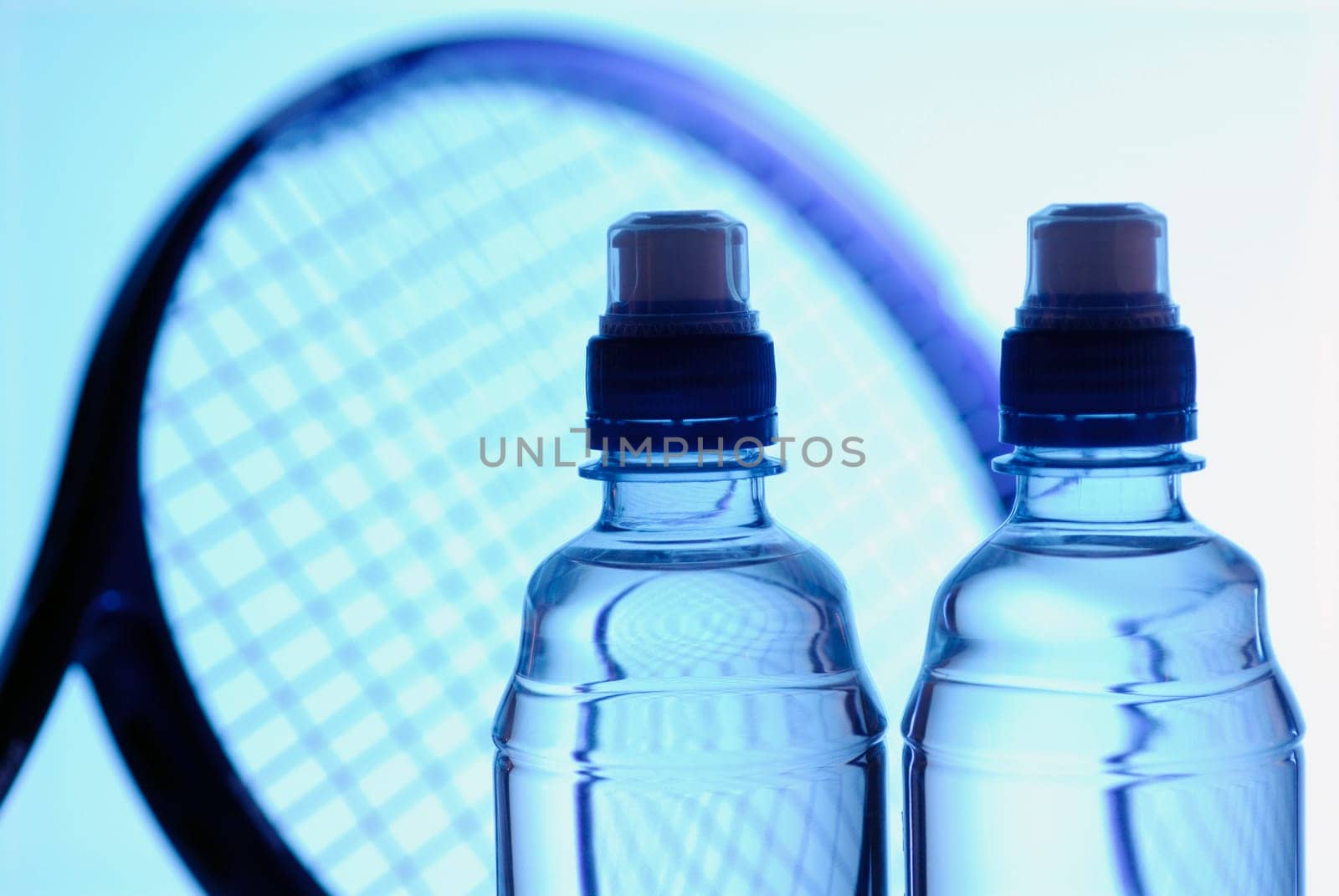 Close-up of two water bottles with a tennis racket