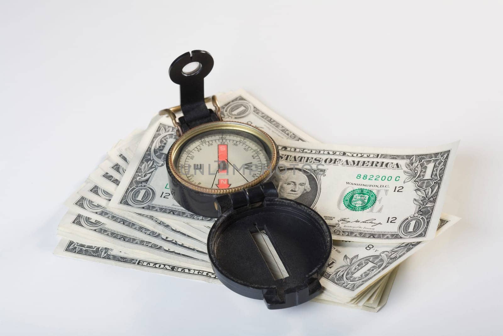 Close_up of a compass on a stack of US dollar bills