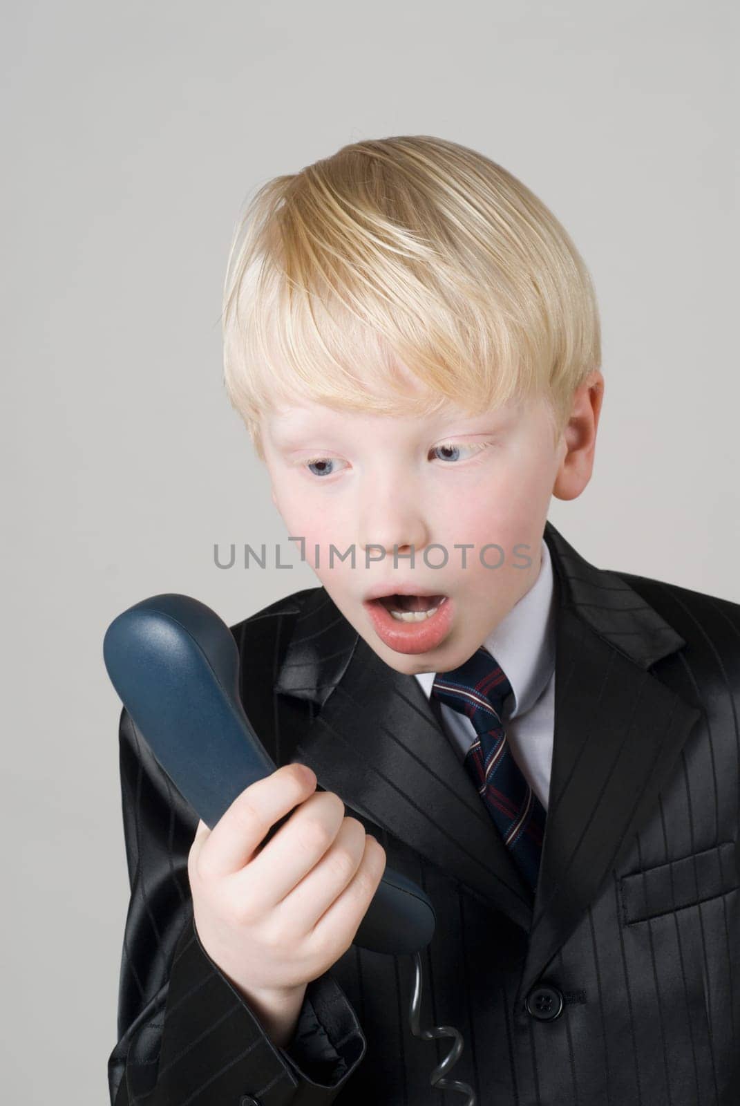 Close_up of a boy looking at a telephone receiver in shock
