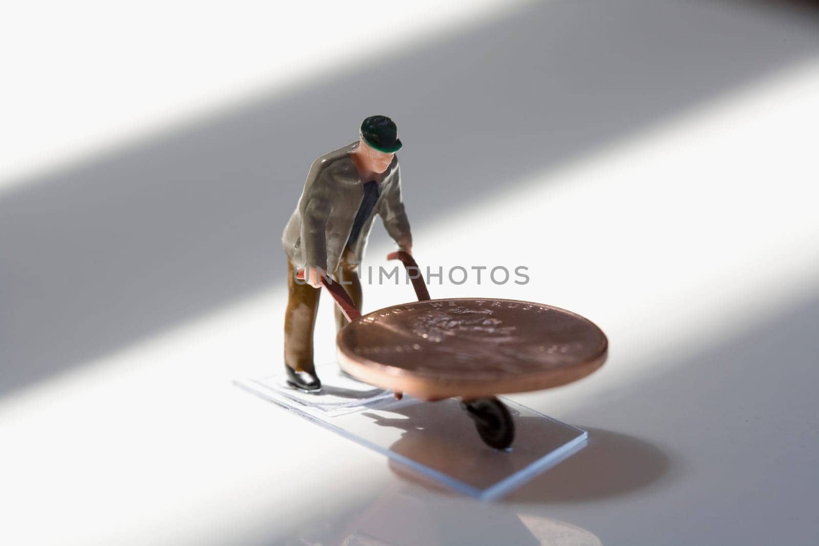 Figurine of a manual worker carrying a coin on a wheelbarrow