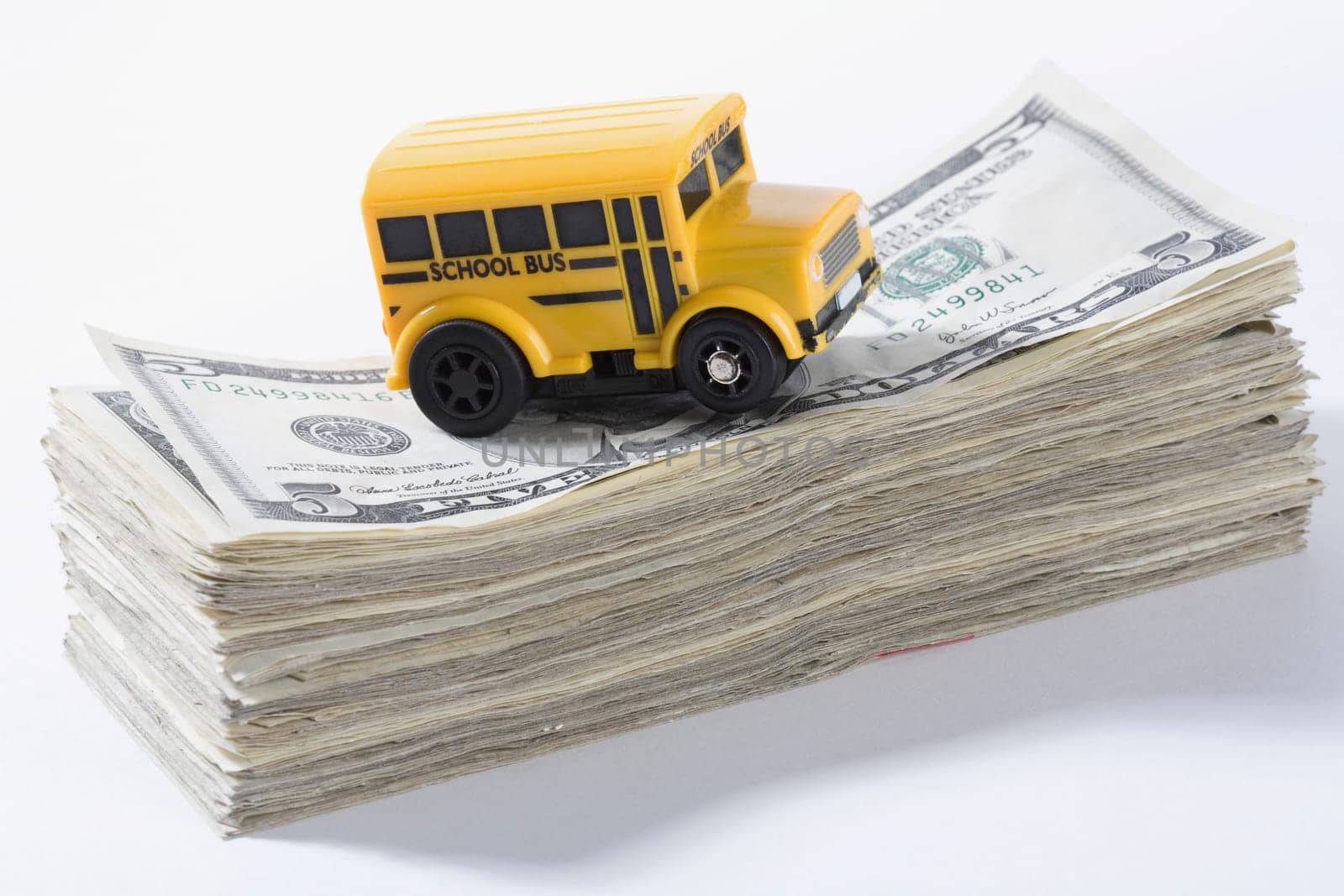 Close_up of a toy school bus on a stack of US dollar bills