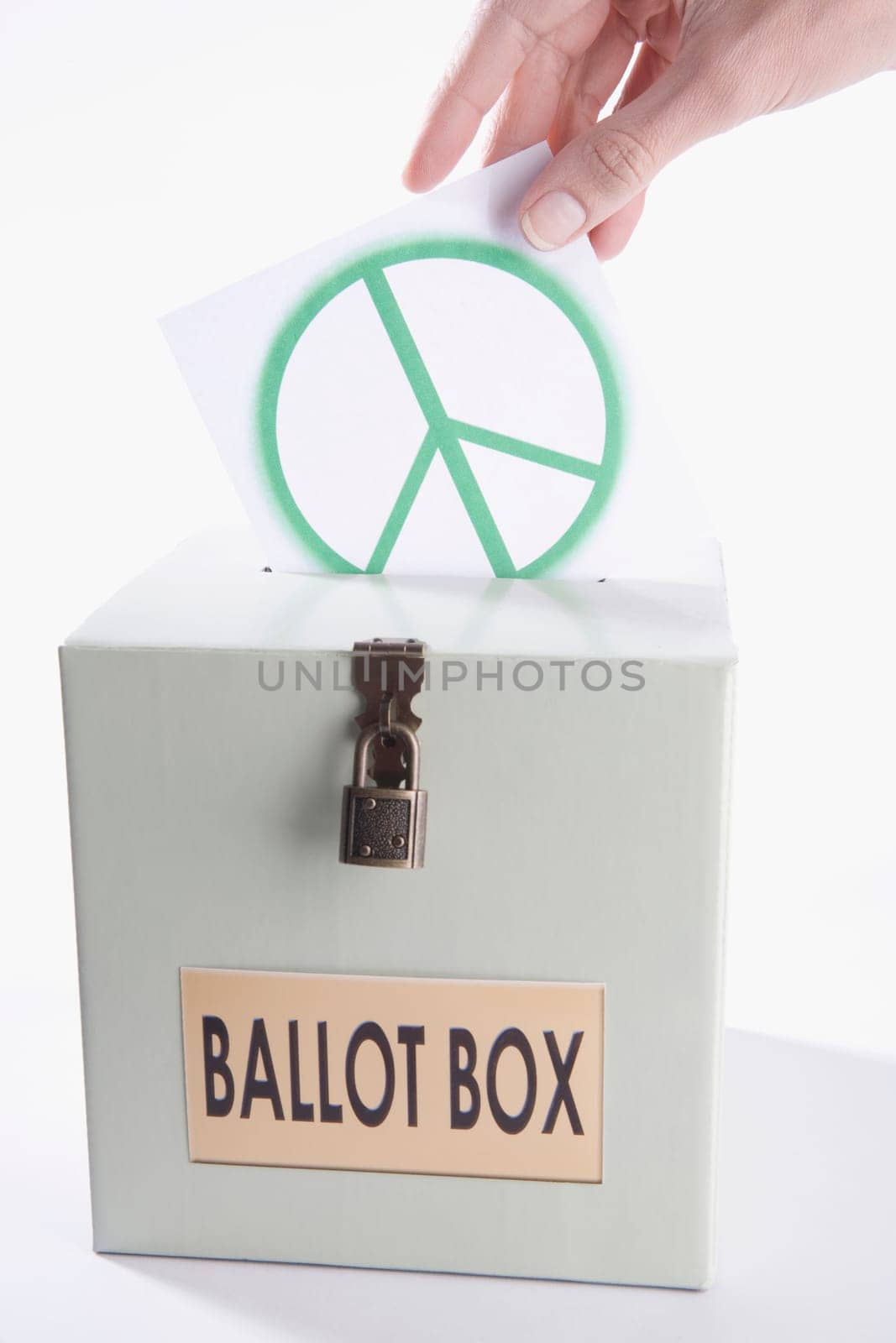 Close_up of a personŽs hand inserting a world peace symbol vote into a ballot box