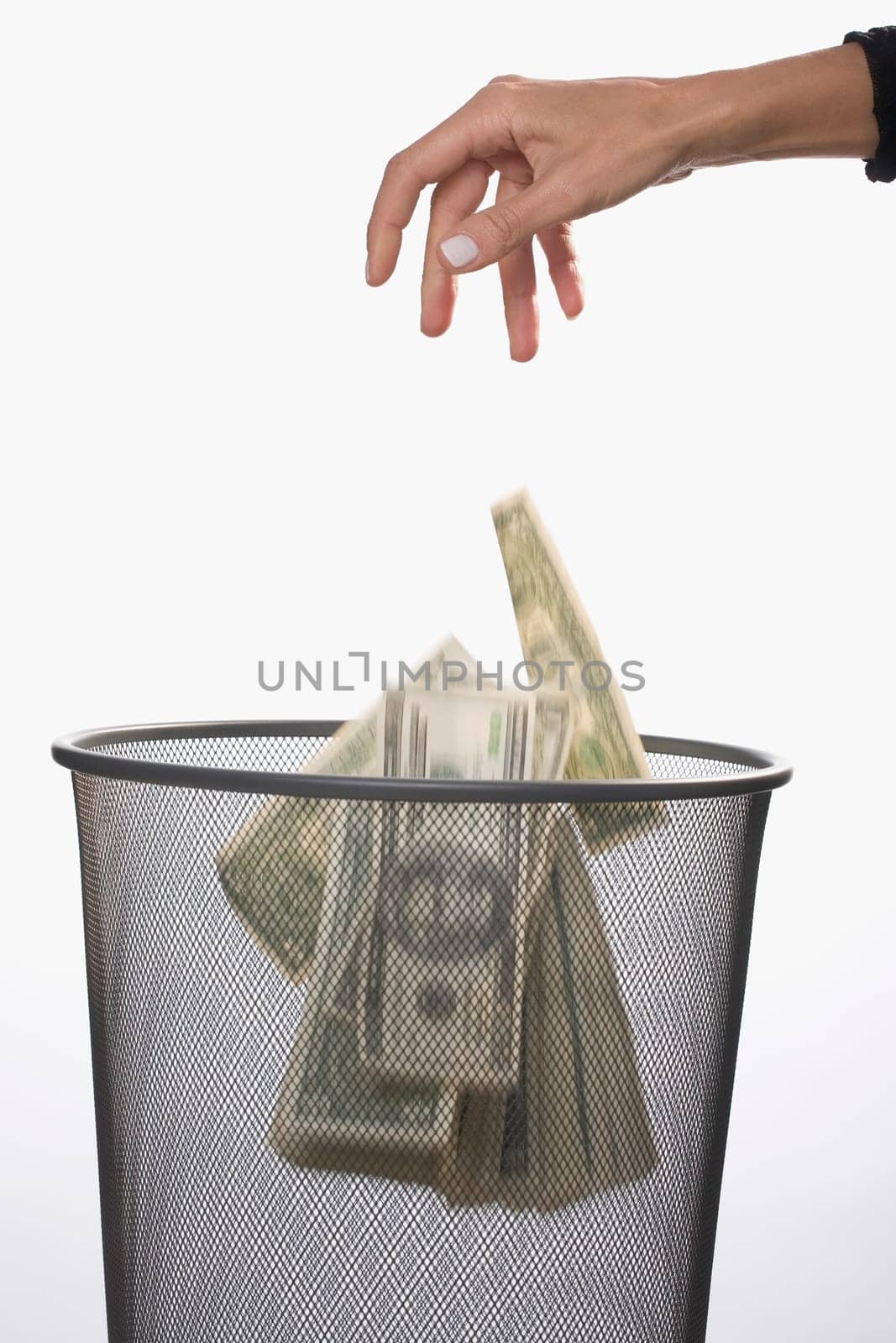 Close_up of a personŽs hand throwing US dollar bills in a garbage bin