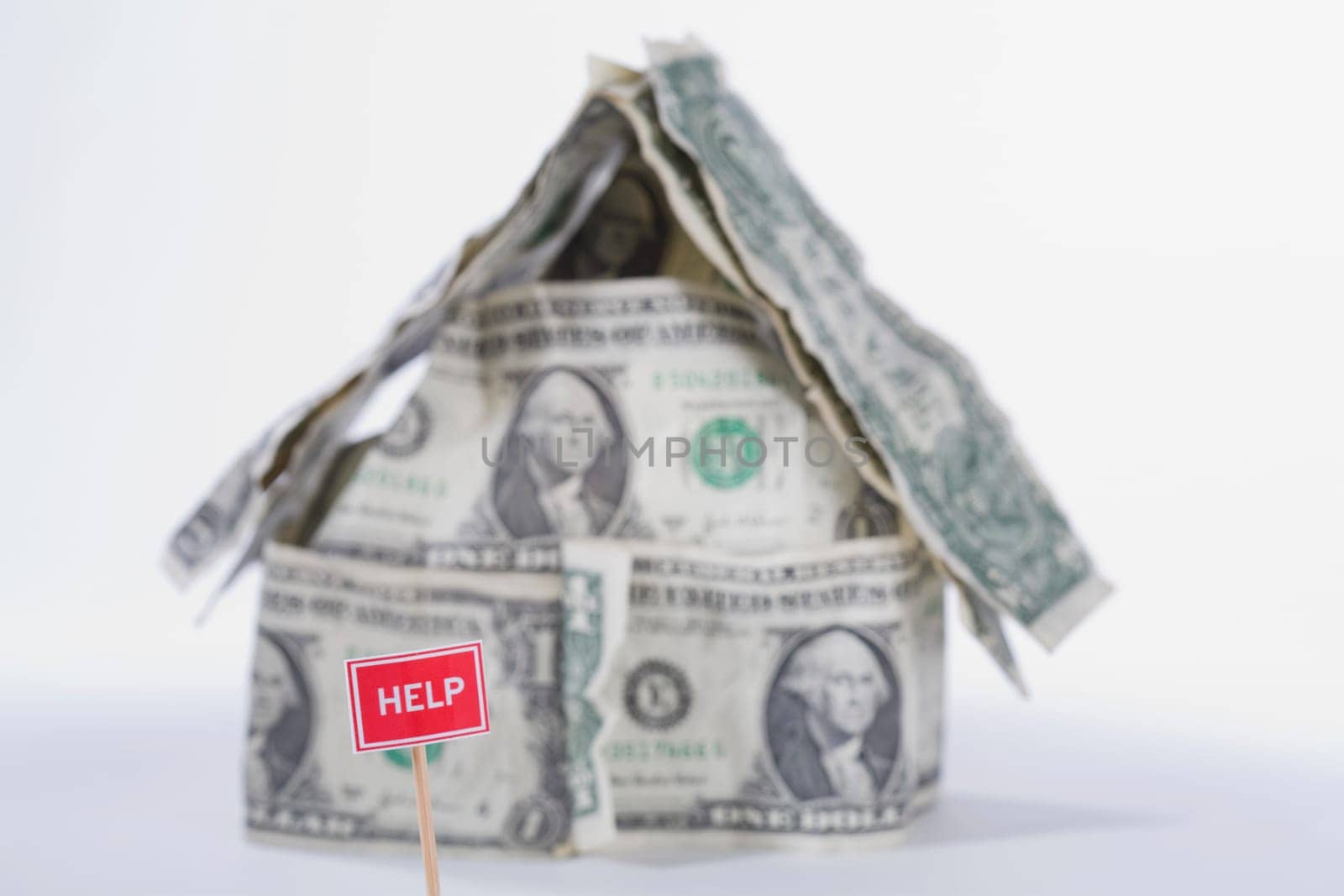 Help sign board in front of a miniature house made by US dollar bills