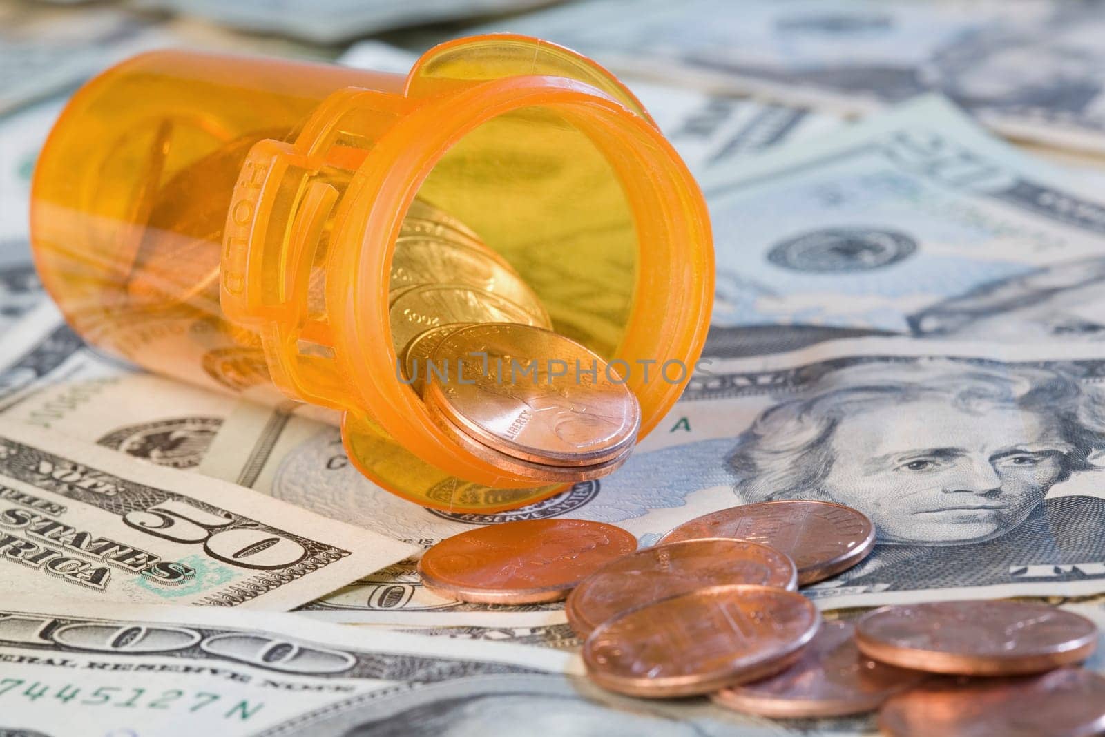 Close_up of coins and pill bottle on US paper currency