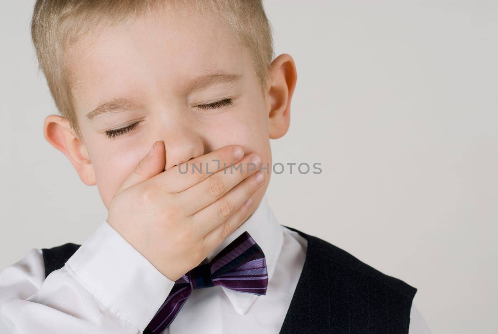 Close_up of a boy covering his mouth with his hands