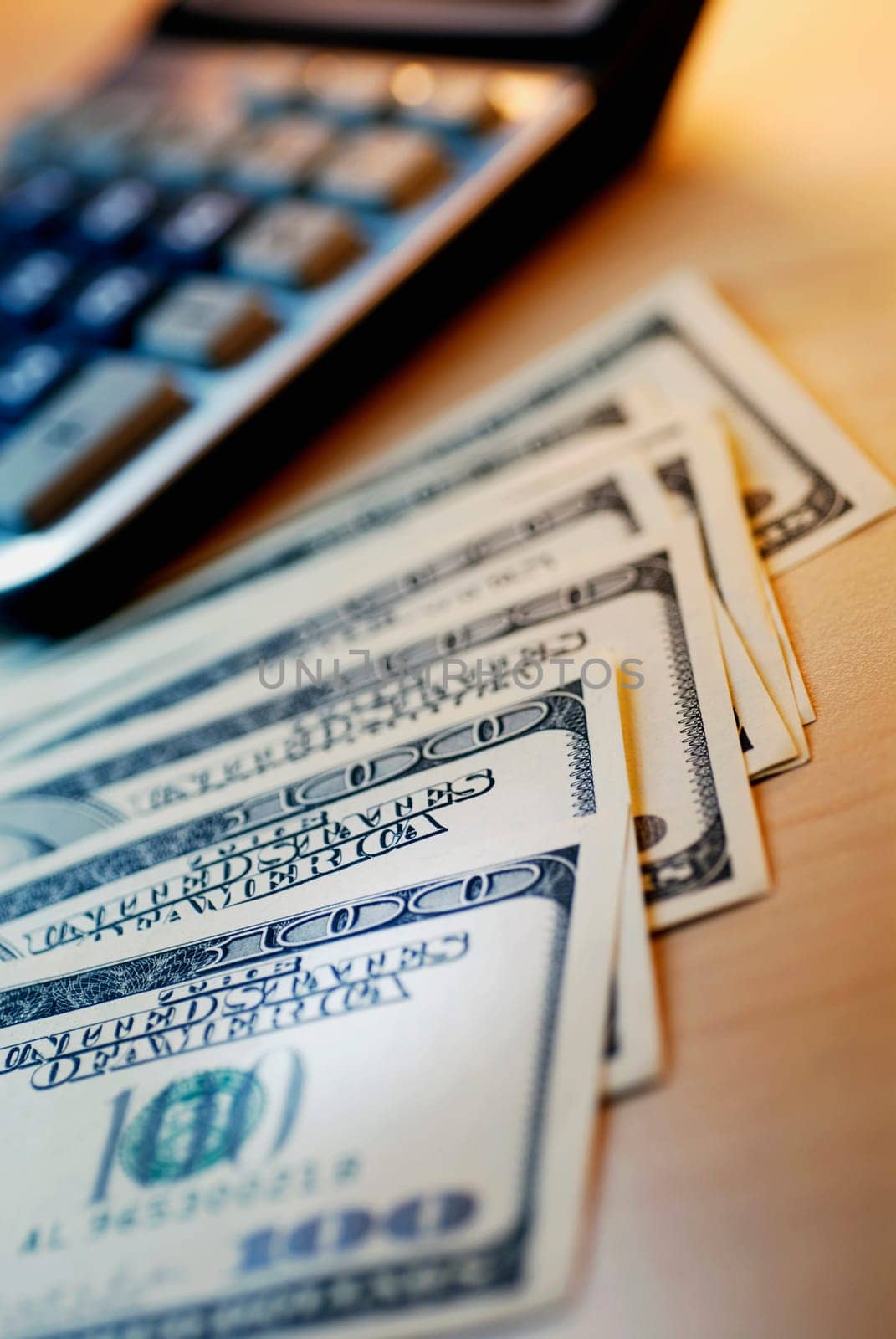 Close-up of one hundred dollar bill with a calculator
