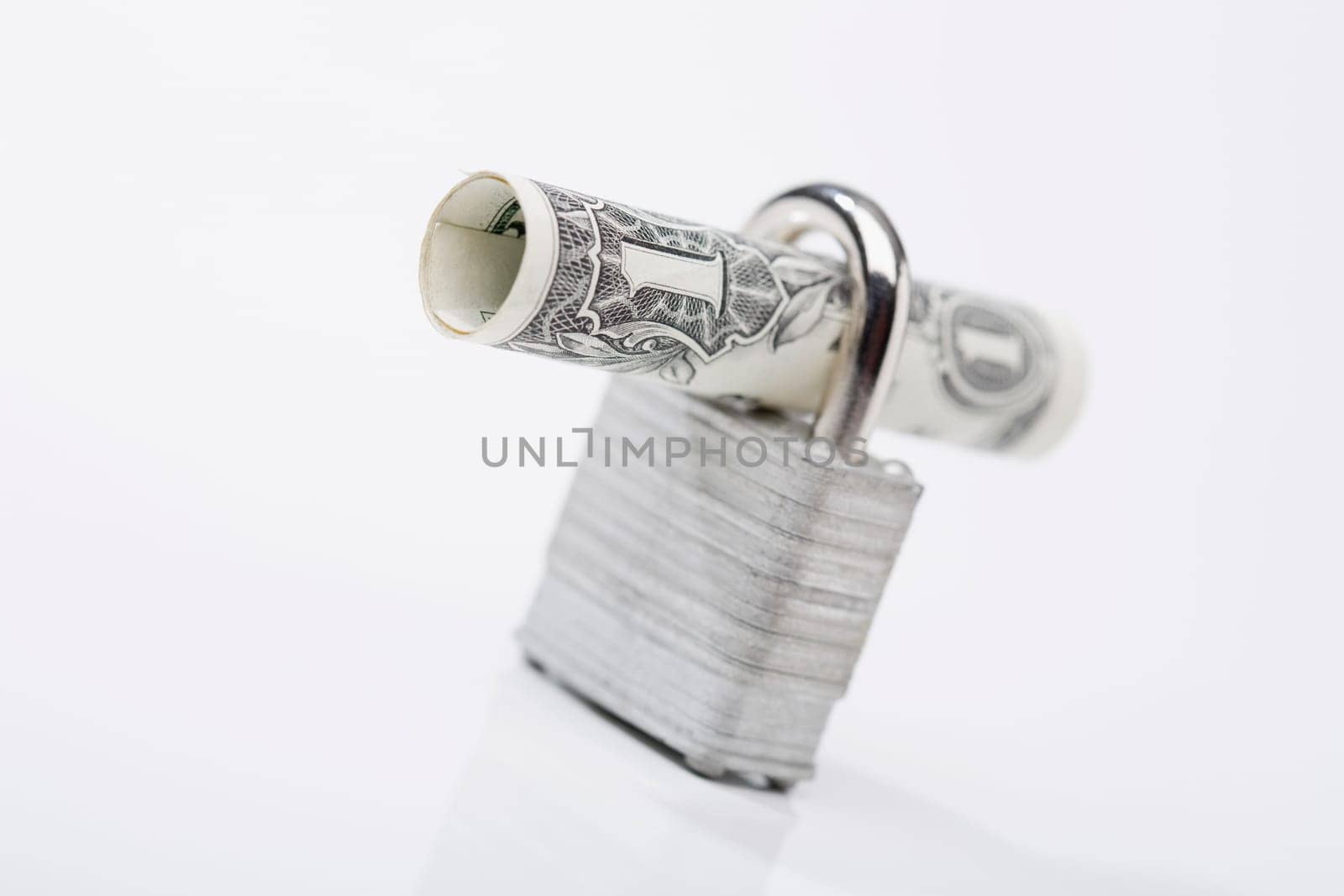Close_up of a rolled bank note with a padlock
