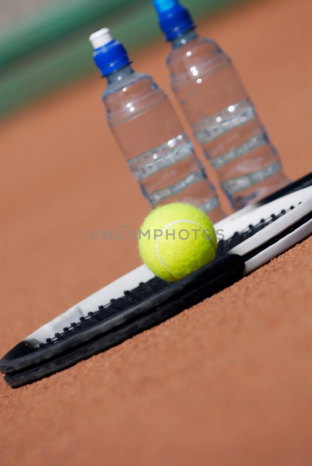 Close-up of a tennis racket and a tennis ball with two water bottles