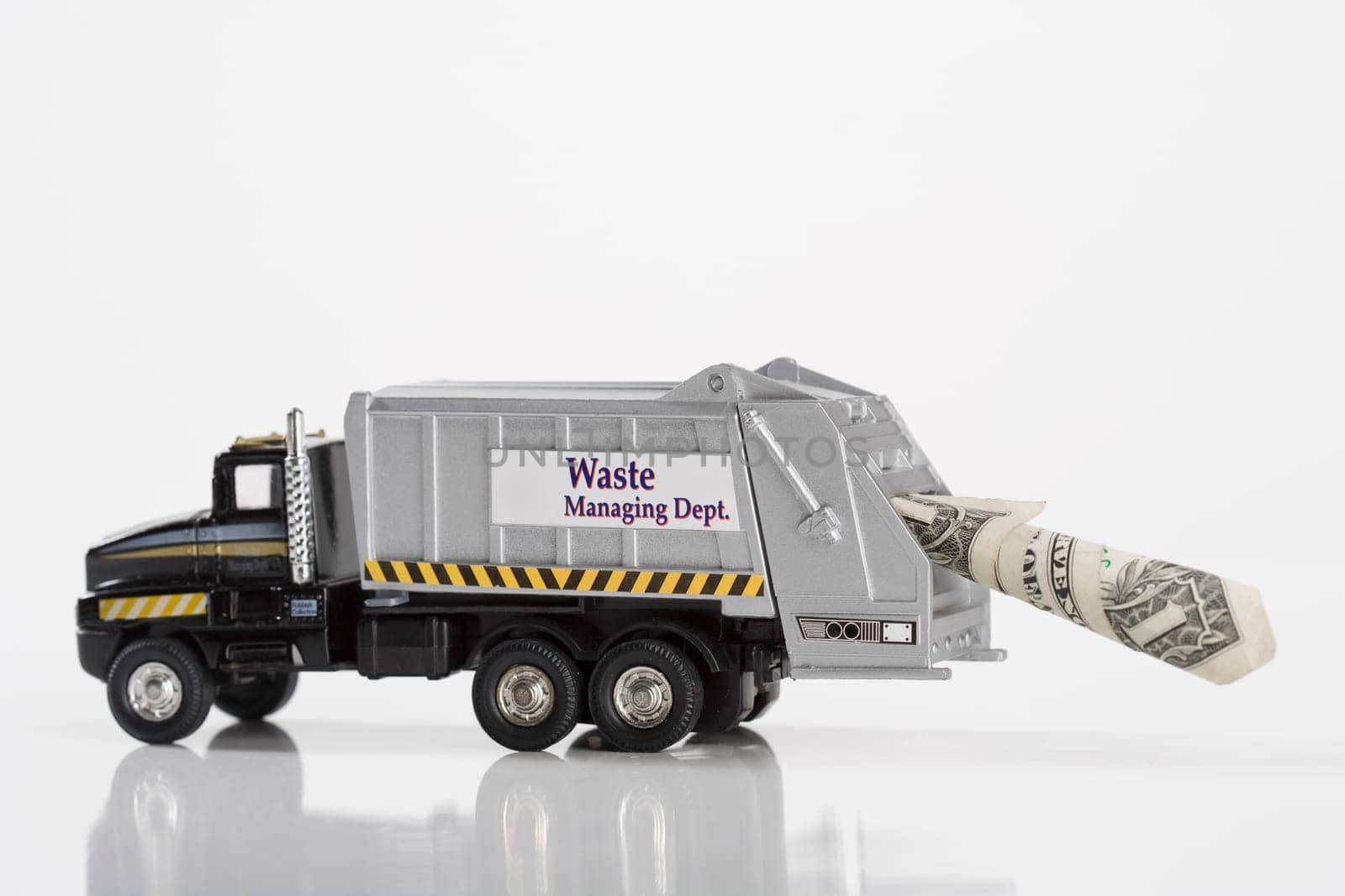 Close_up of toy garbage truck carrying US dollar bill