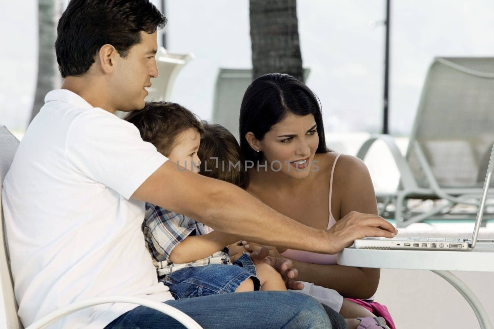 Parents with their two children sitting in front of a laptop