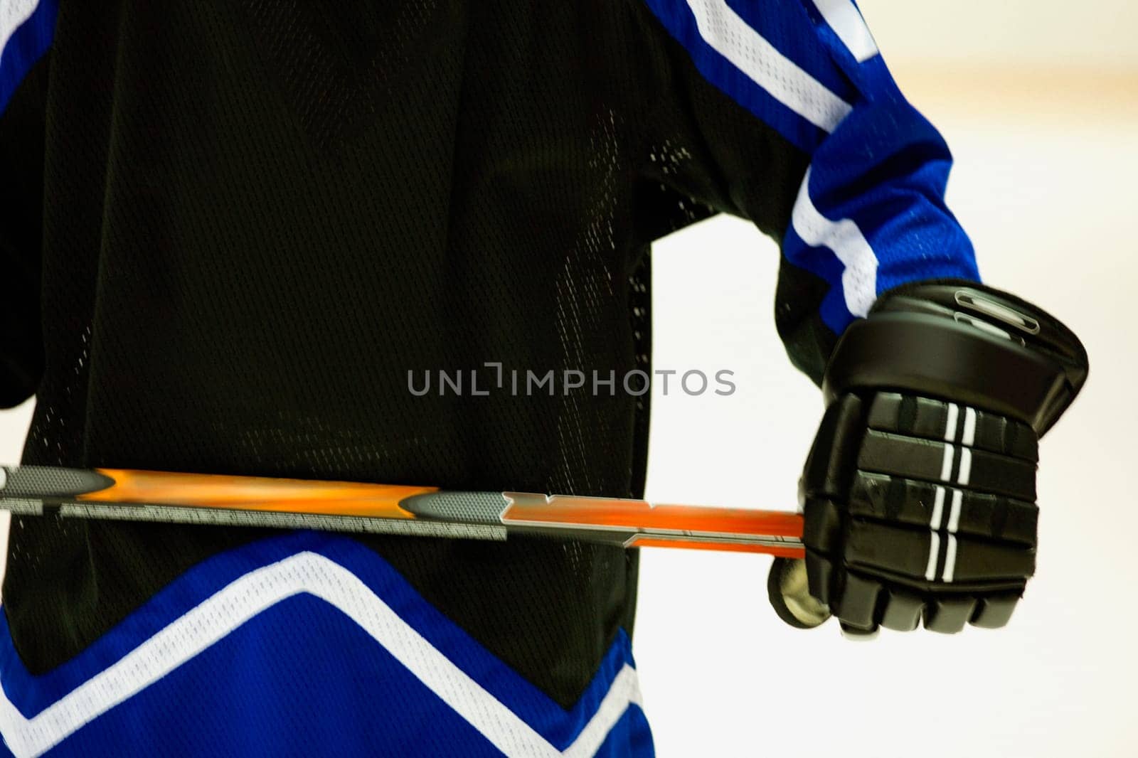 Mid section view of an ice hockey player holding an ice hockey stick