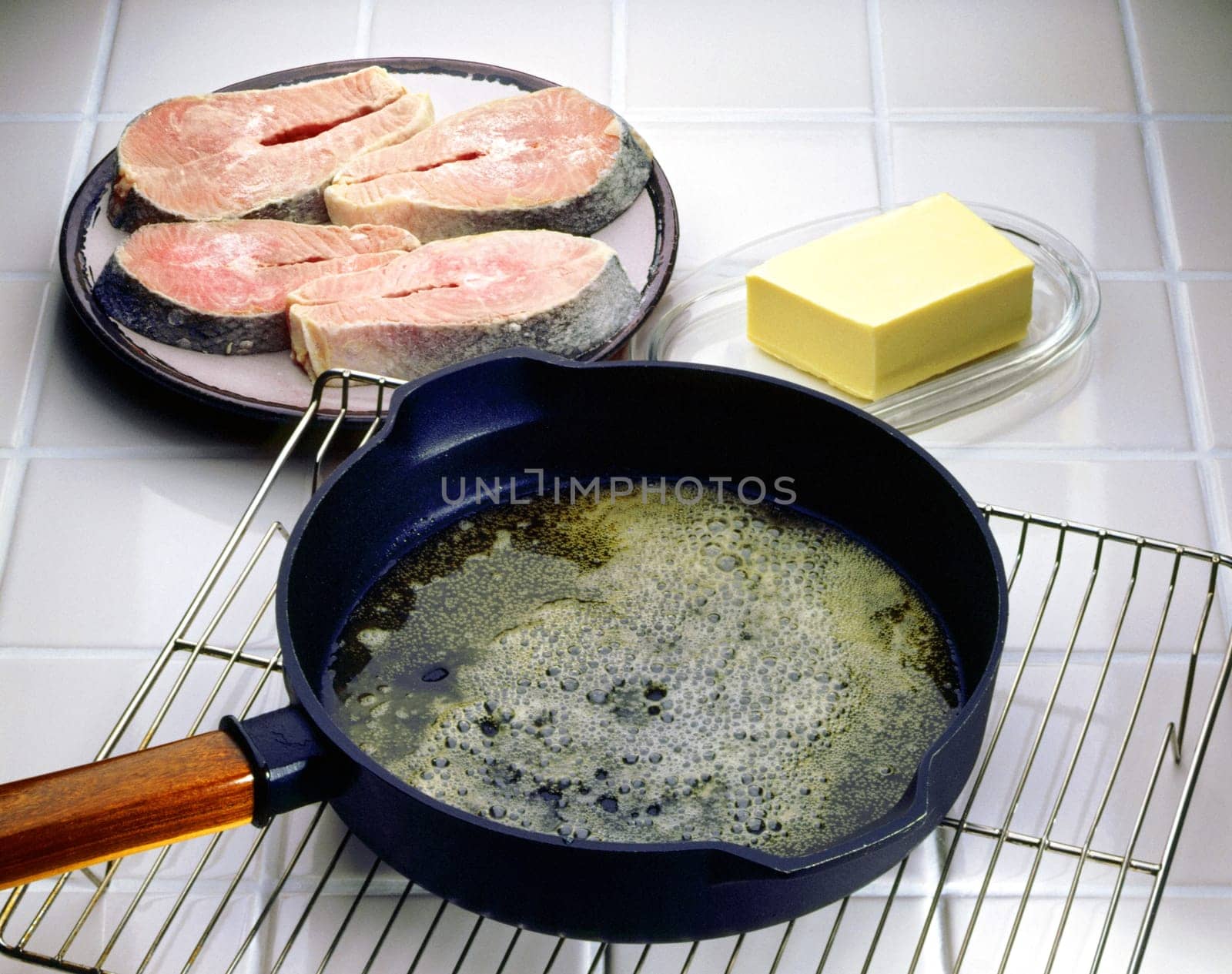 Close-up of a frying pan on a cooling rack with salmon beside it
