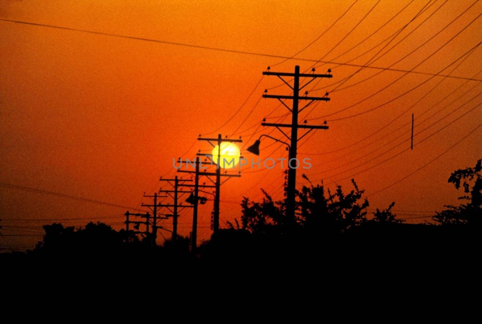 Silhouette of electricity pylons and power lines at sunset