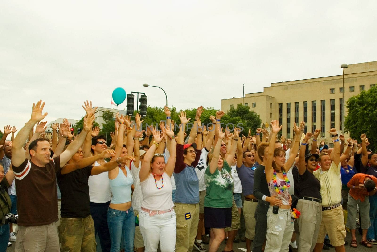 Large group of people waving their arms at a gay parade