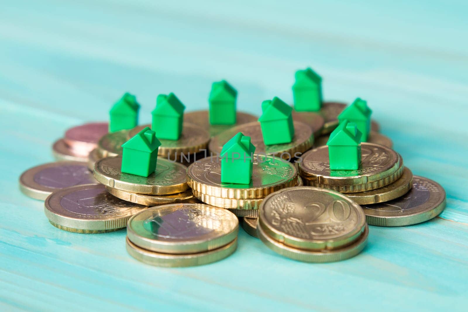 Miniature houses resting on coins pile. Concept for property ladder, mortgage and real estate investment