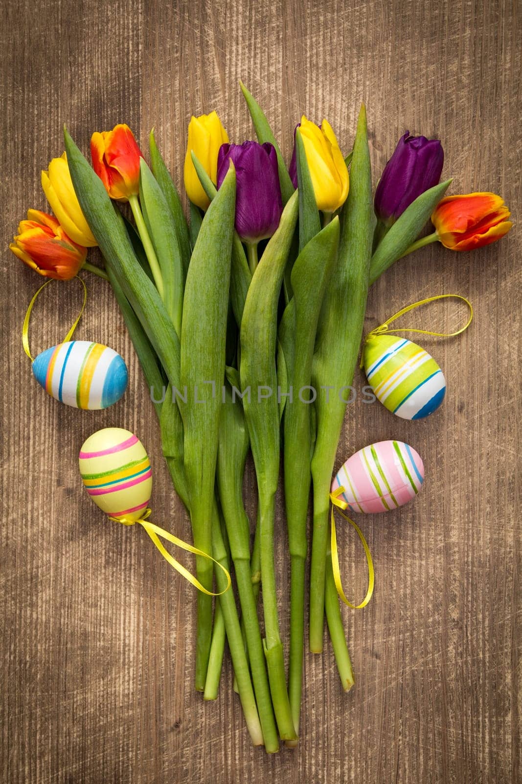 Easter eggs and colorful tulips bouquet on wooden background