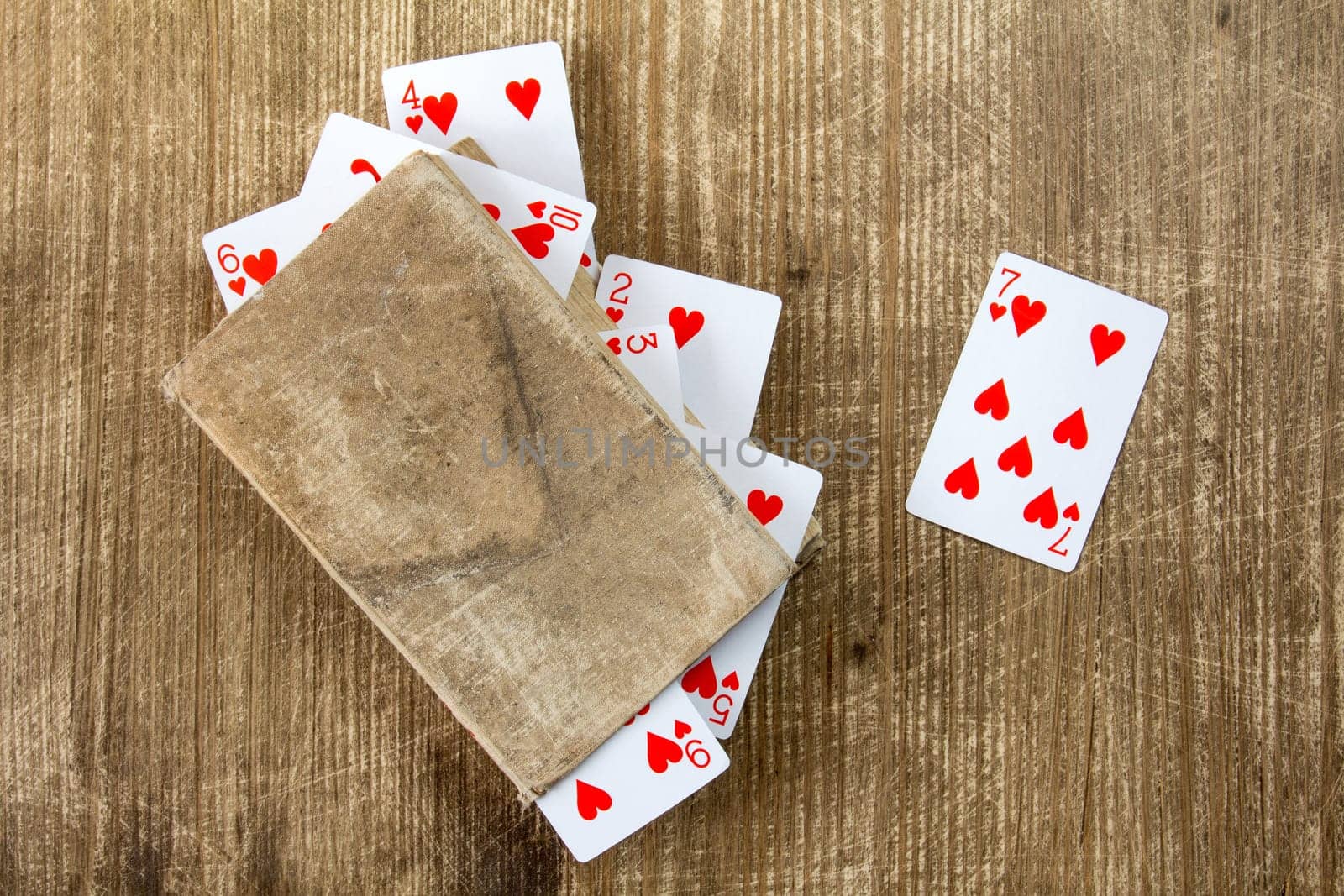 Old book and playing cards on wooden background