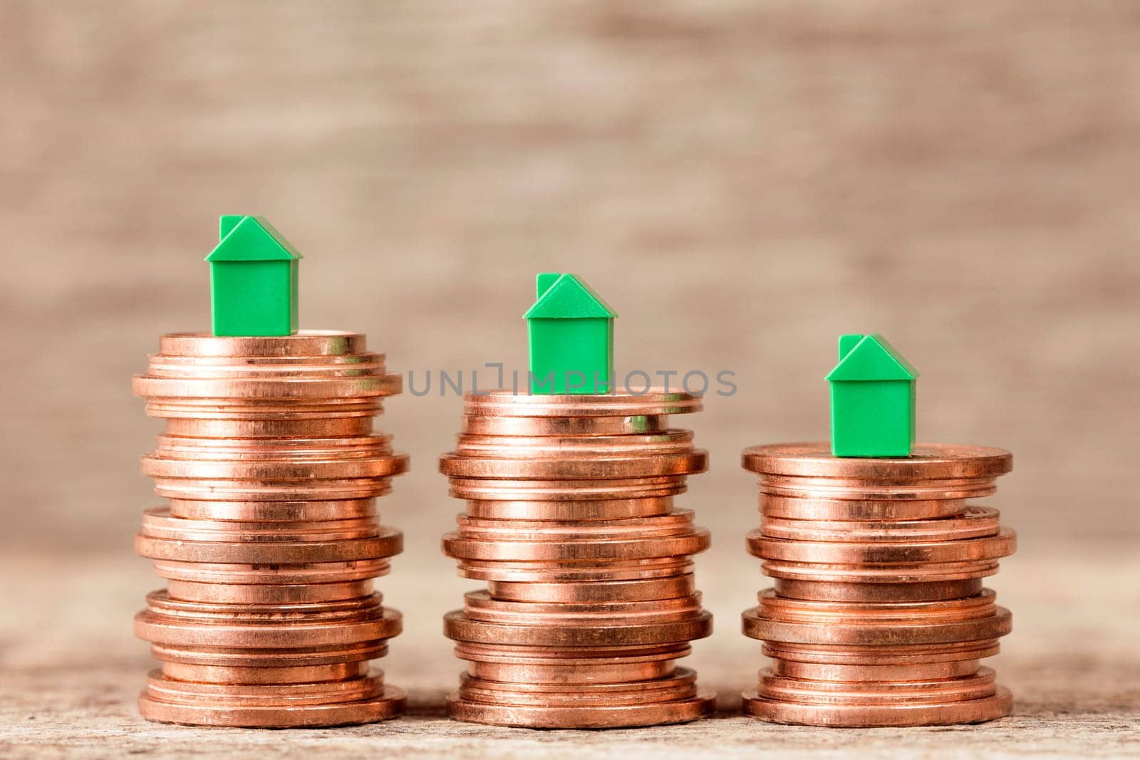 Three stacks of coins with mini houses on the top. Concept for property ladder, mortgage and real estate investment