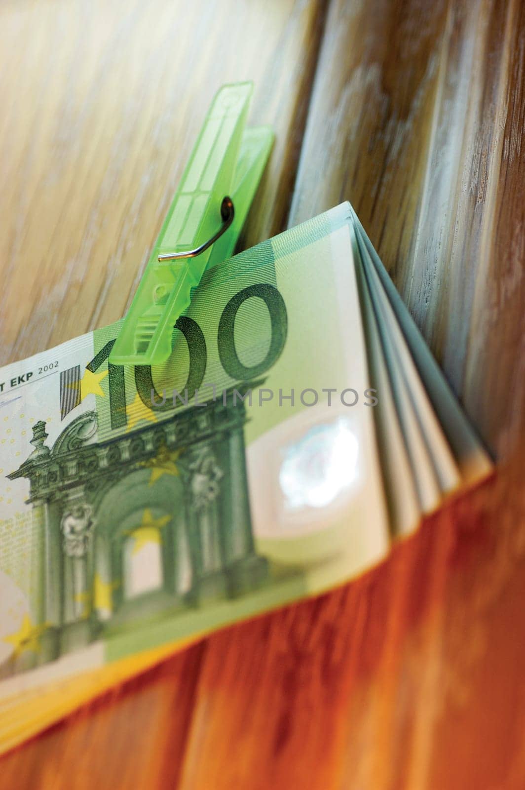 Close-up of clothes peg on a stack of one hundred Euro banknotes